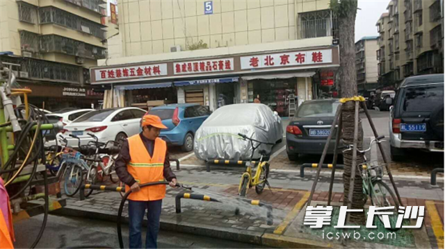 毛正宏抓着水枪进行路面冲洗。