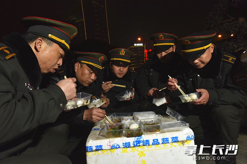 寒风瑟瑟中，焰火结束后天心区城管队员草草地扒了几口盒饭。长沙晚报记者 陈飞 摄