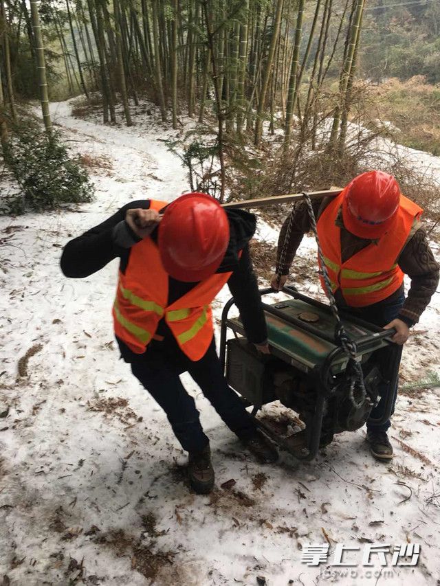 长沙移动一线抢修人员冒着雪，肩挑设备进山，抢修通信设施。