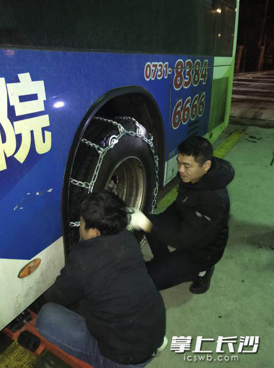 维修工人和驾驶员连夜给公交车安装防滑链条