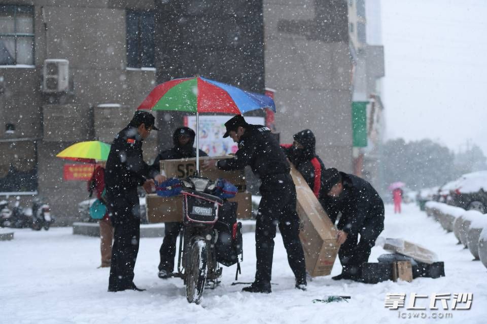 芙蓉区上东辛顿小区，一快递小哥骑车不慎滑倒，小区物业人员帮小哥扶起车，并帮他重新放好货物。长沙晚报记者 黄启晴 摄