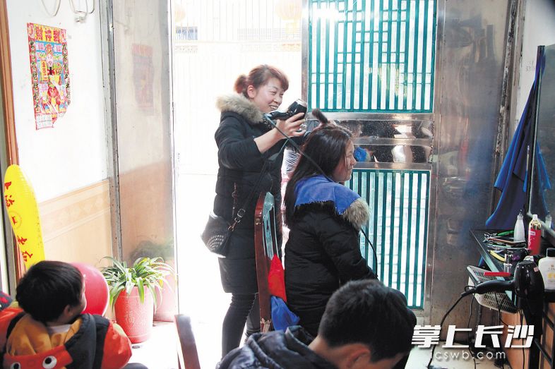 平价理发店里暖意融融，和善的老板娘正在为顾客吹干头发。 长沙晚报记者 张禹 通讯员 杨柏松 摄影报道