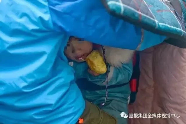 躲在挡风被下的女儿没有任何玩具，只有一个干面包。