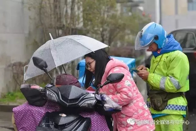 一位好心的姑娘在雨中给孩子撑起伞，李帮勇在旁边顾不上照顾女儿。