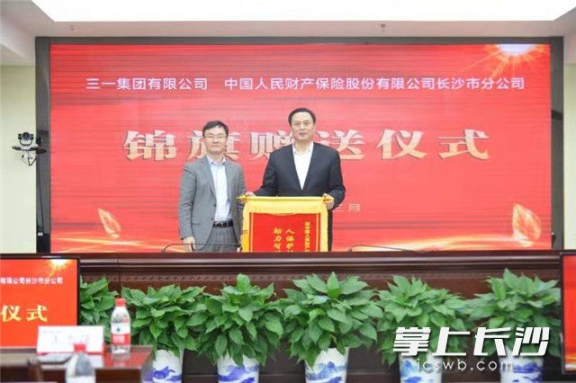 三一集团高级副总经理兼三一新能源投资有限公司总经理王志强（左）将写有“人保护航实体经济，助力智能制造腾飞”的锦旗送到人保财险长沙市分公司，图右为人保财险湖南省分公司副总经理兼长沙市分公司总经理廖文常