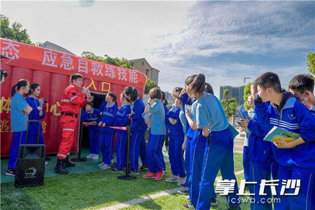 在临时搭建的烟雾逃生屋外，湖南省应急管理协会防灾应急体验馆教官现场指导中南大学附属第二中学的孩子和社区居民们参加火灾逃生练  均为长沙晚报全媒体记者 陈飞 摄