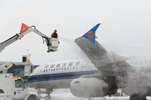 黄花机场停机坪，工作人员为飞机去除冰雪。