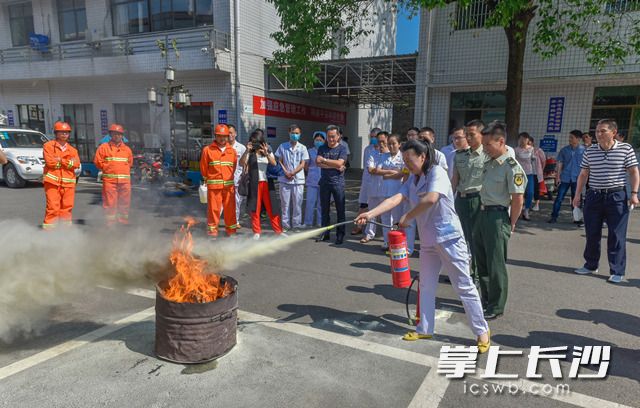 消防官兵正给卫生所工作人员进行了灭火训练，手把手教大家使用干粉灭火器。长沙晚报记者 陈飞摄