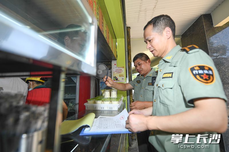 在岳麓区天马路一处门店，城管执法人员正在耐心劝说店主将店外经营的柜子撤进门店。长沙晚报记者 黄启晴 摄