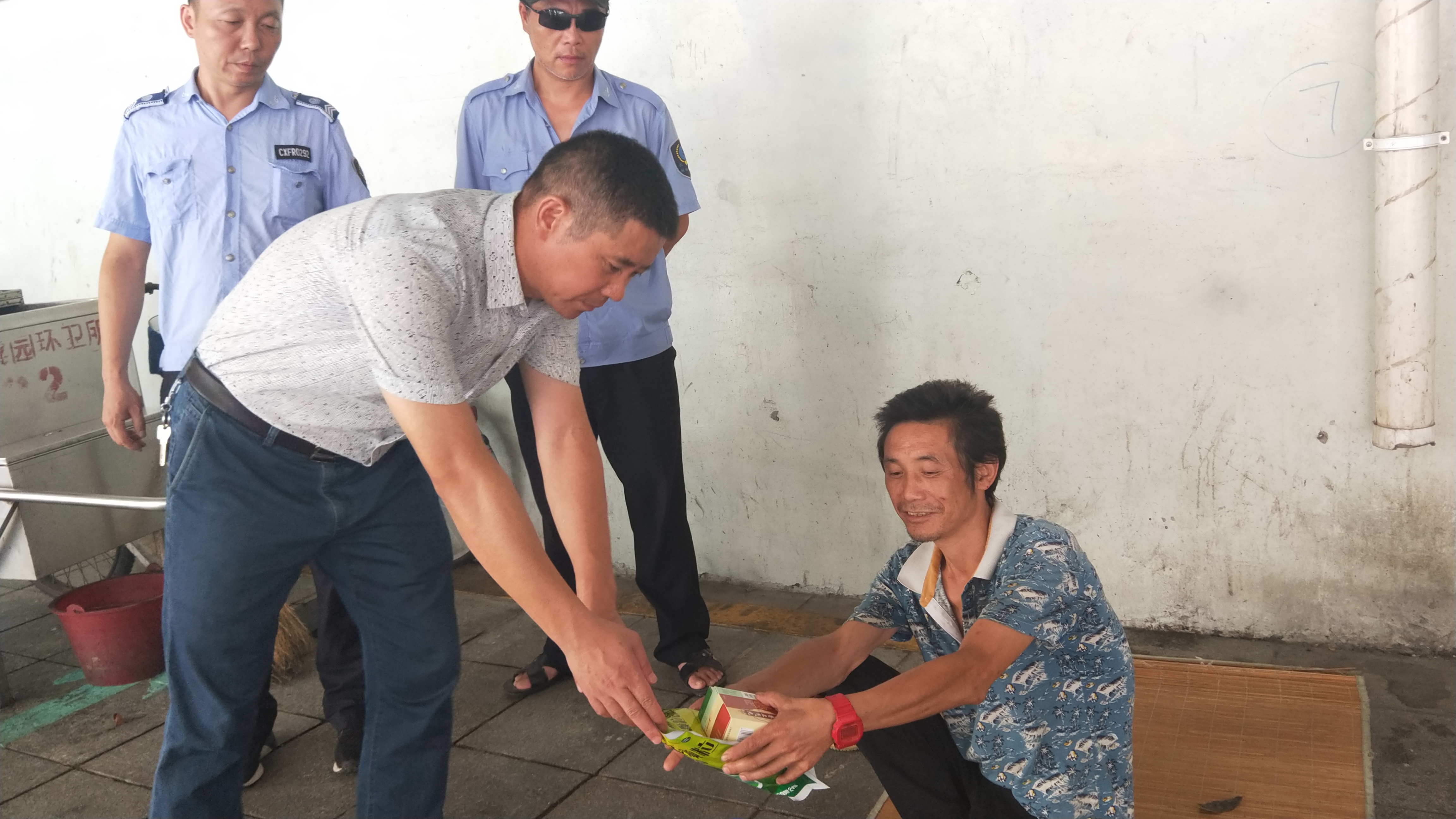 酷暑中，面对地下通道的流浪人员，韭菜园街道工作人员协助其联系家人，并送上凉茶、清凉油、藿香正气水等降暑物品。长沙晚报通讯员 罗灵子 摄