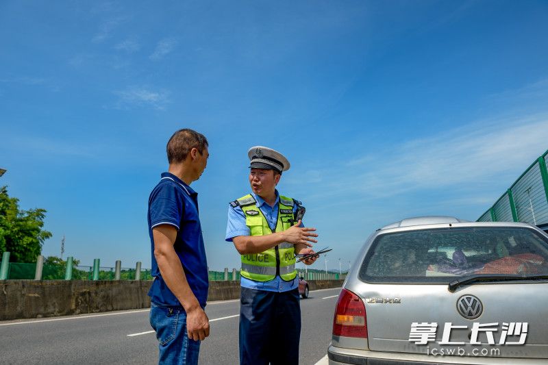 高速公路上，巡逻的刘飞发现一台故障车辆停在应急车道，连忙下车查看情况。见驾驶员未按规定在车辆后方摆放三角警示标志，刘飞对其进行批评教育。