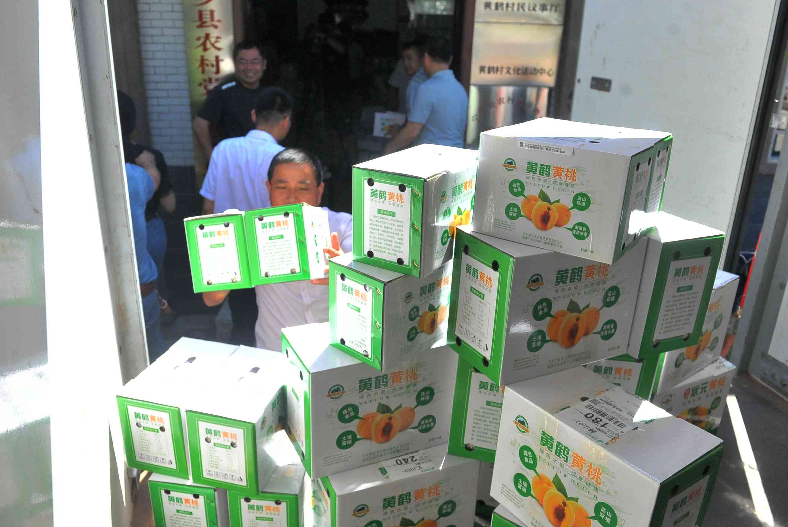 种桃户将一箱箱黄桃装车，准备发往电商平台。