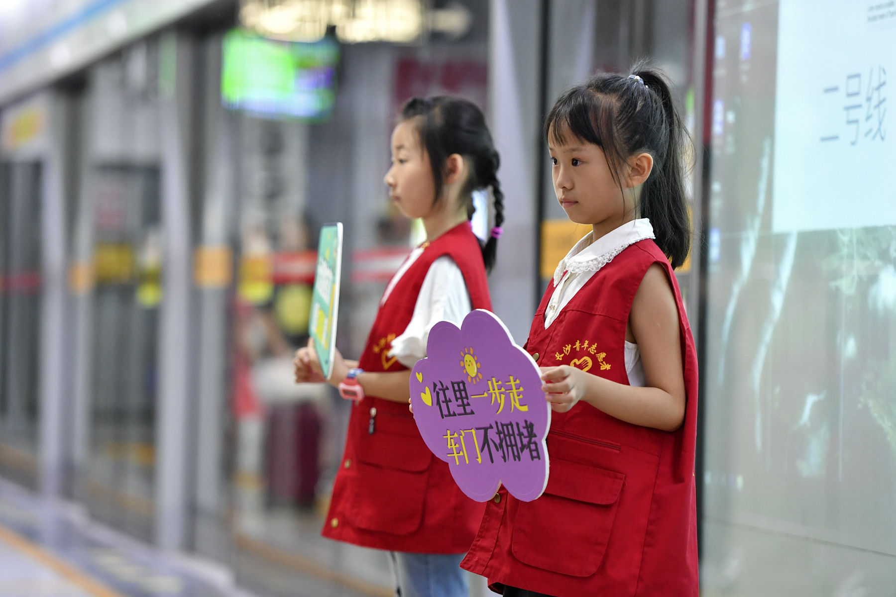 今日上午，长沙地铁五一广场站内，身穿志愿者红马甲的小萌娃在地铁工作人员的带领下一同维护车站内文明秩序，引来乘客纷纷点赞。 长沙晚报全媒体记者 王志伟 摄