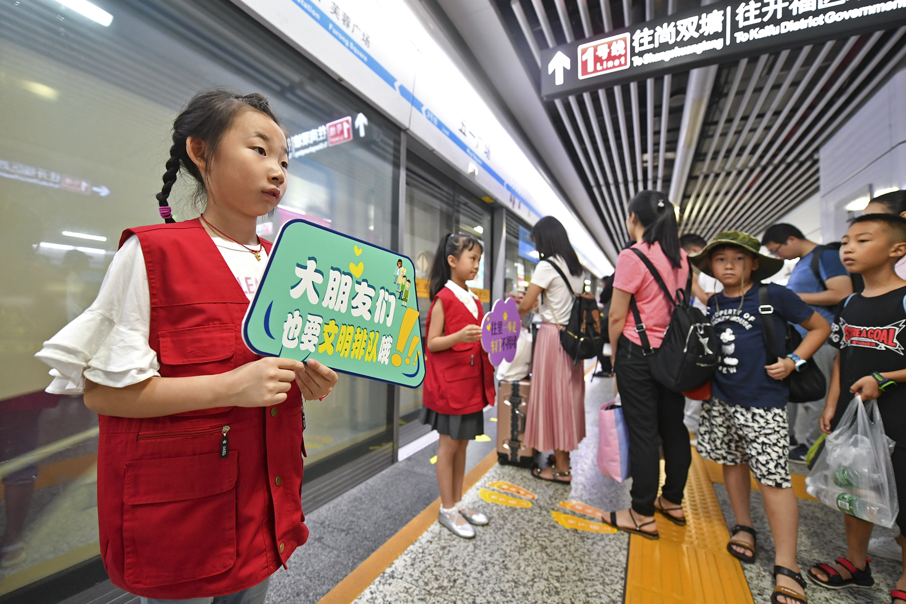 今日上午，长沙地铁五一广场站内，身穿志愿者红马甲的小萌娃在地铁工作人员的带领下一同维护车站内文明秩序，引来乘客纷纷点赞。 长沙晚报全媒体记者 王志伟 摄