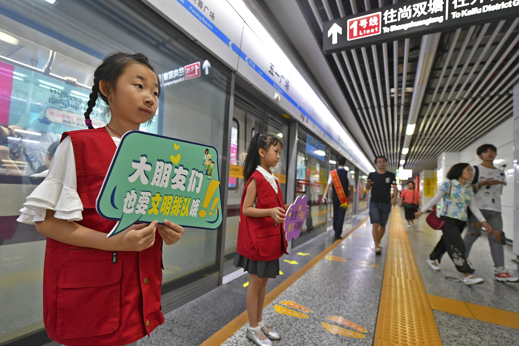 今日上午，长沙地铁五一广场站内，身穿志愿者红马甲的小萌娃在地铁工作人员的带领下一同维护车站内文明秩序，引来乘客纷纷点赞。 长沙晚报全媒体记者 王志伟 摄