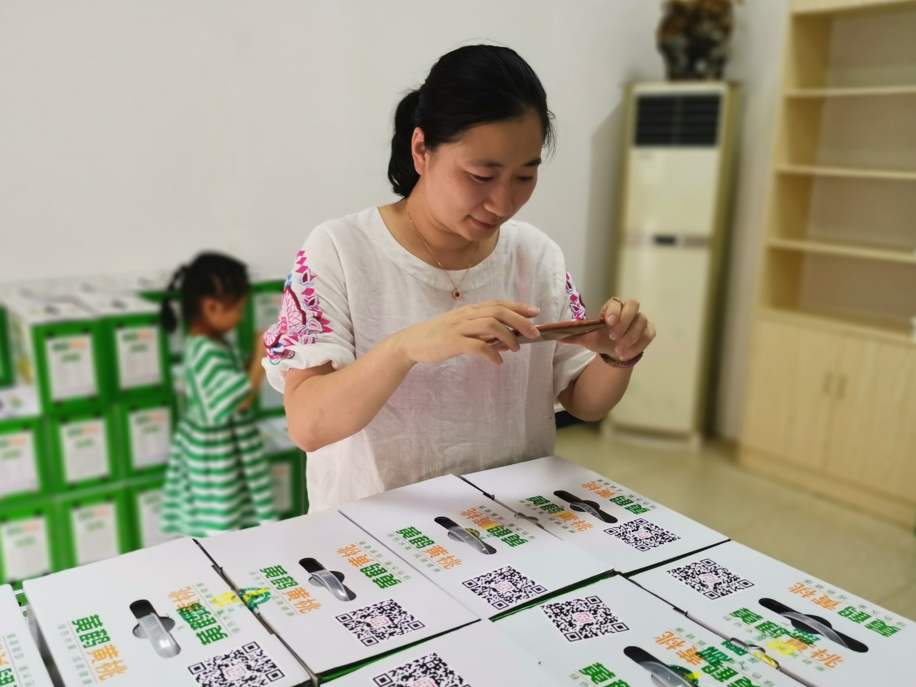 一位消费者在购买黄鹤黄桃时用手机扫二维码，了解产品的详情。 全媒体记者 张禹 通讯员 姜润辉 摄影报道