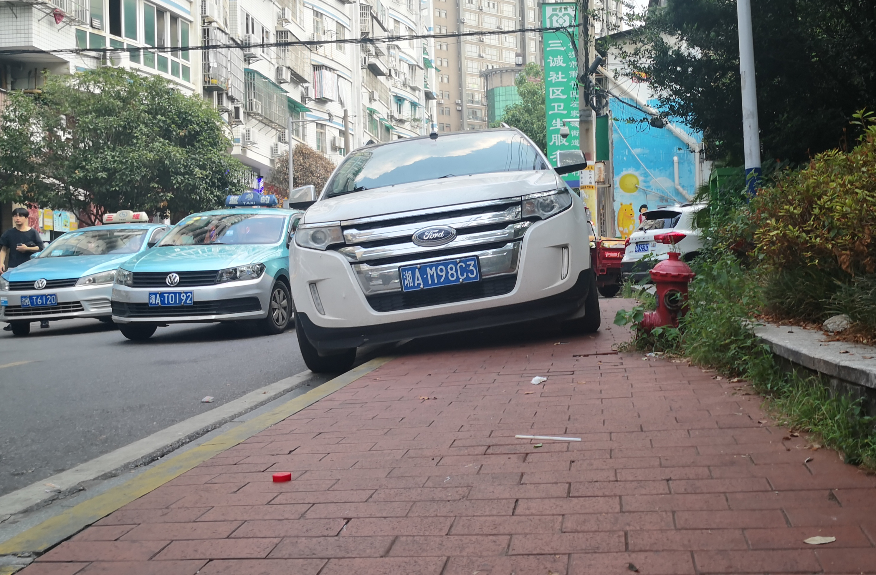 桂花树街路边人行道上，一辆私家车“骑”在路边停放着。