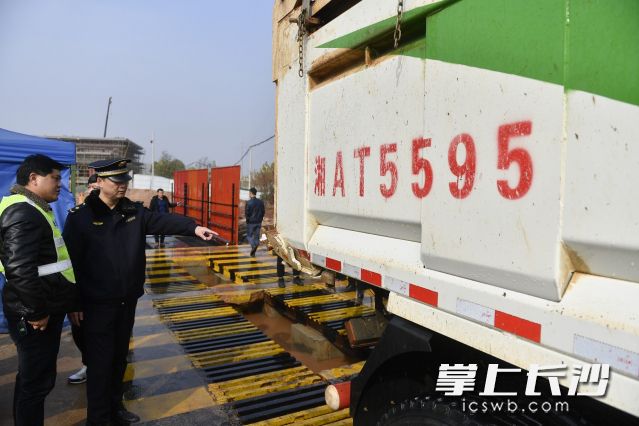 今年起长沙城区渣土运输将全面实施错时错峰出行，按照禁行路段、核心区域、中心区域、外环区域，分四类区域优化调整渣土运输时间。在芙蓉南路一建筑工地，一辆装满渣土的运输车正在工地内进行清洗作业，同时城管执法人员对车辆进行相关检查。长沙晚报全媒体记者 余劭劼 摄