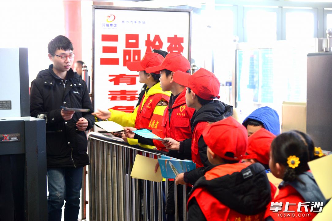志愿者们在进站口为旅客发放《长沙市文明行为促进条例》。