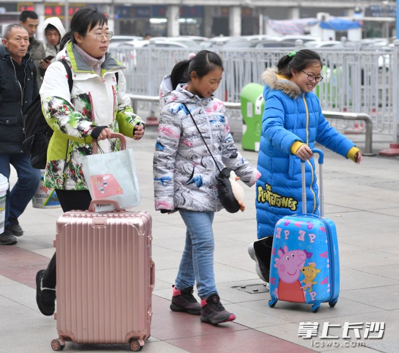 一位小朋友推着一个小猪佩奇图案的行李箱高兴不已。