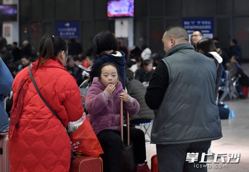 长沙火车站候车室，一位小朋友坐在行李箱上休息。