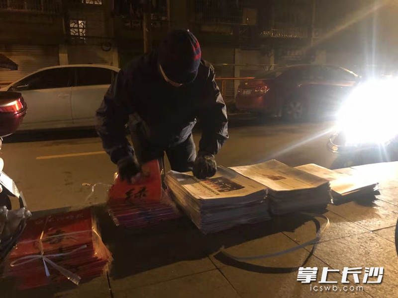 凌晨5时许，借着微弱的路灯和电动车灯，发行员们抓紧时间夹报。