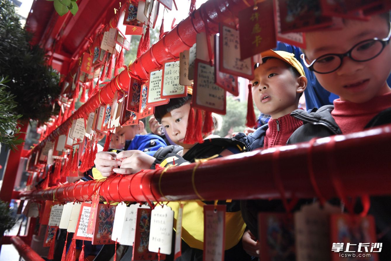 在坡子街火宫殿，孩子们把自己的新年愿望挂在祈愿板上，为新年祈福。图片均为长沙晚报全媒体记者 邹麟 摄