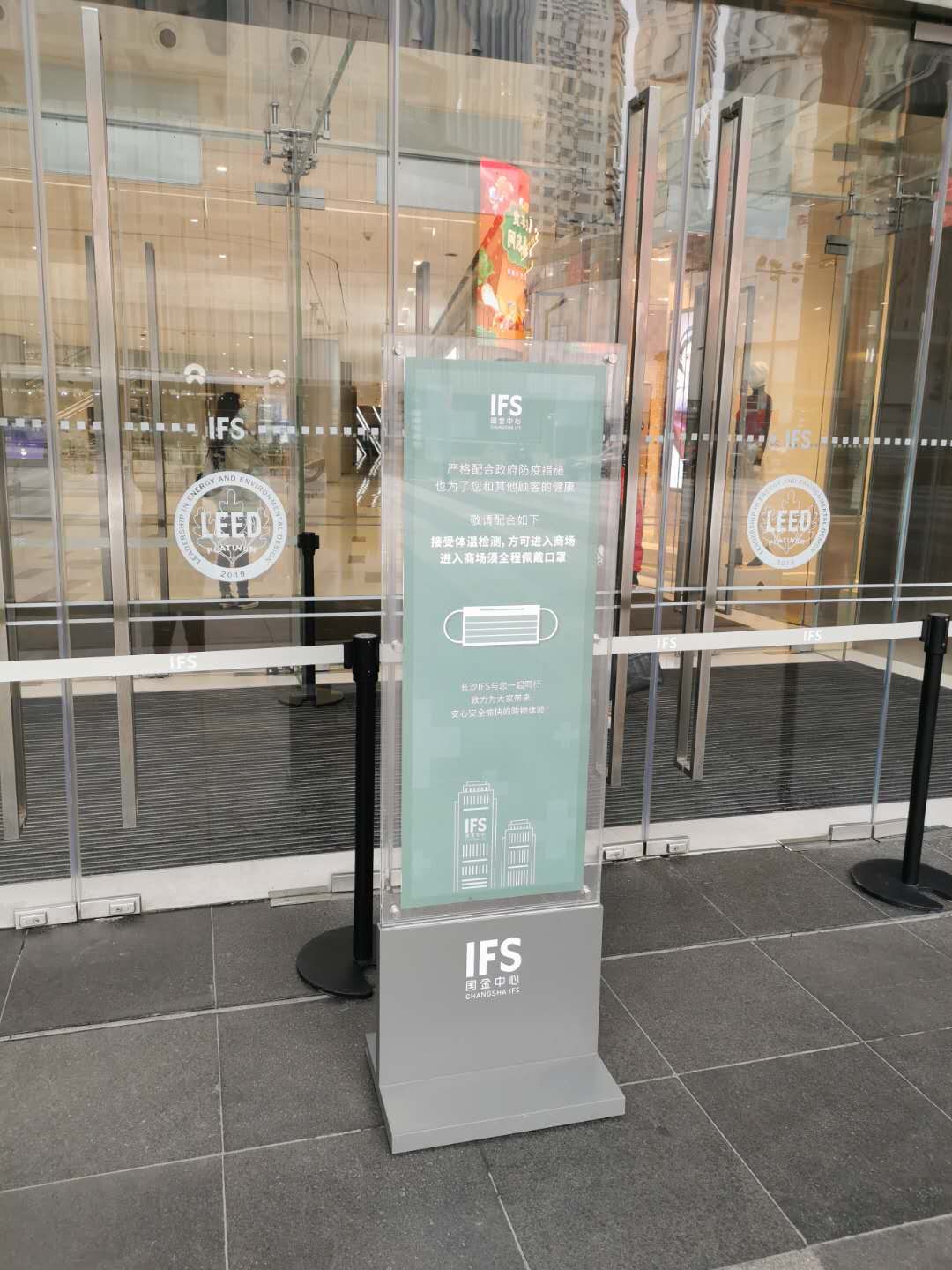 商场门口立有体温检测、佩戴口罩的提示牌。