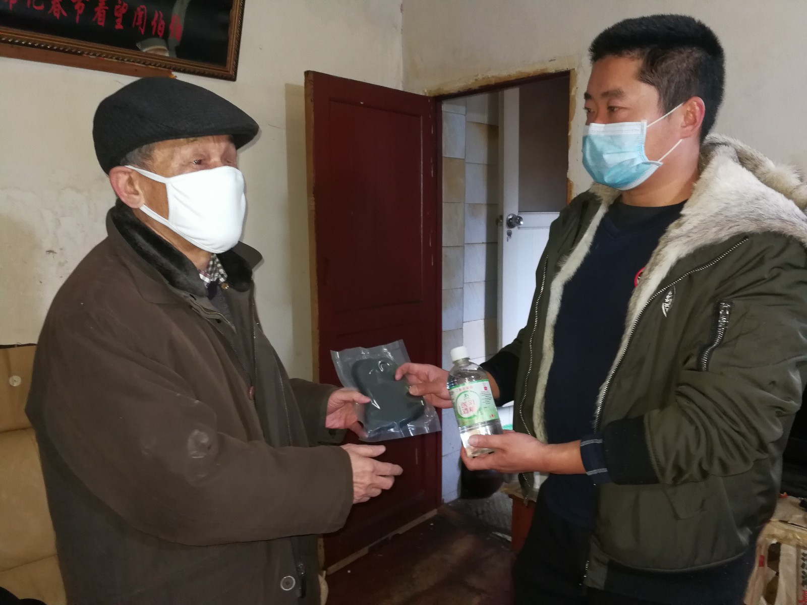图为汤俊杰（右）来到裕南街孤老残疾人闻先铭家中，给老人送来了5只口罩、1瓶医用酒精消毒液等物资。长沙晚报全媒体记者 黎铁桥摄