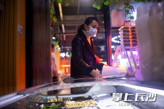 王曼在社区的商铺里，查看店铺的消毒卫生情况。