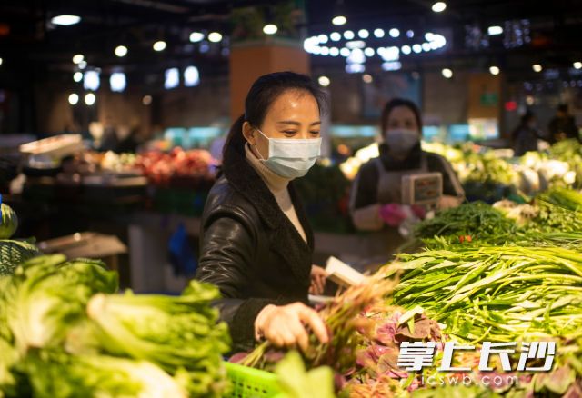 在社区内的农贸市场，王曼在询问店主销售和消毒情况。 