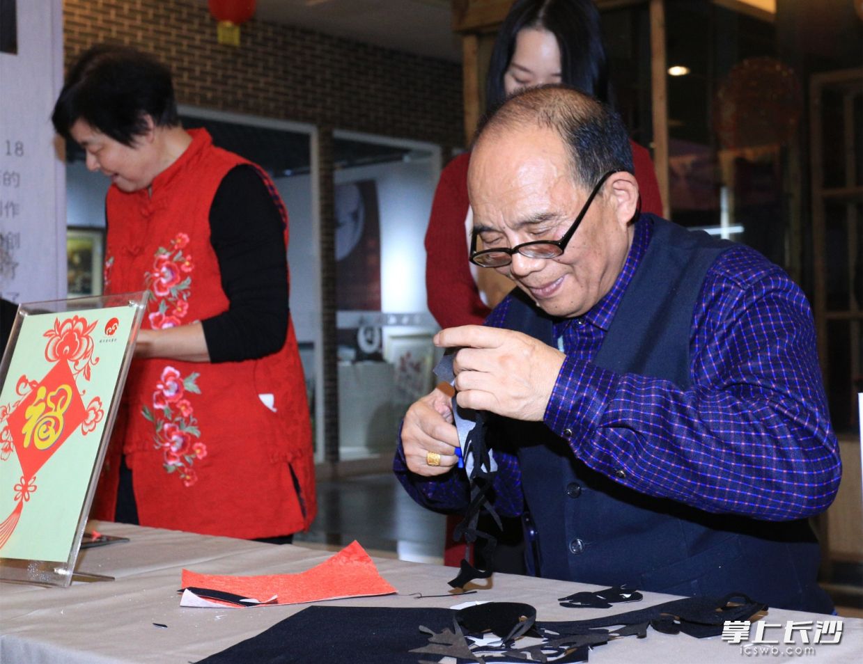 洪源自创了“一刀剪”，能用剪刀不间歇地剪出一个字、一行字甚至一群字，创作时的他更是精益求精。  长沙晚报通讯员 胡国良 摄