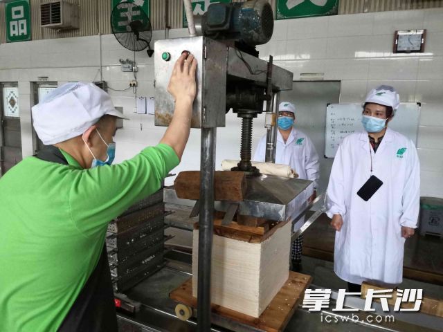 长沙市利利平食品有限公司董事长周利平（右一）在豆制品生产车间检查产品质量。