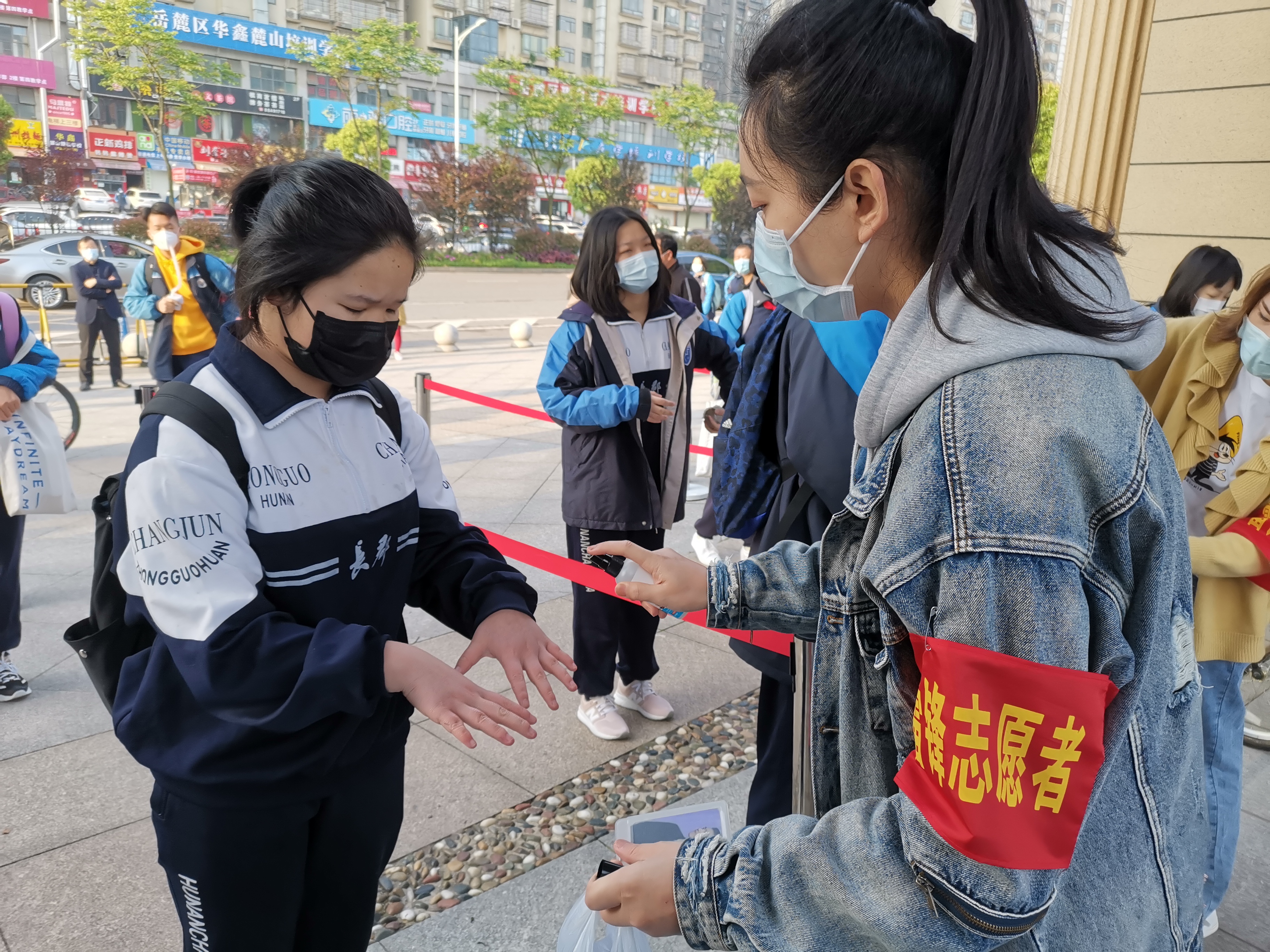 在长郡滨江中学，“雷锋志愿者”们坚守校门，为复学学生开展测温、手部消毒等志愿服务。