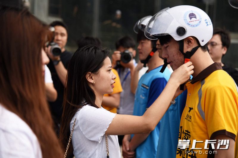 活动现场，外卖小哥彭伟的女友为他戴上安全头盔，十分甜蜜。长沙晚报全媒体记者 刘琦 摄