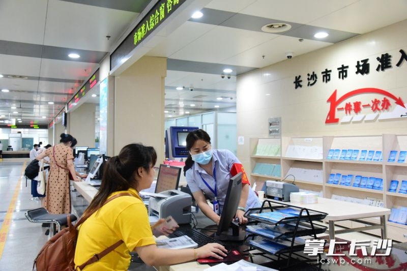 在长沙市政务服务中心，市场监管窗口工作人员在为前来办理业务的市民，一步步示范系统操作的要点。 周辉霞摄 