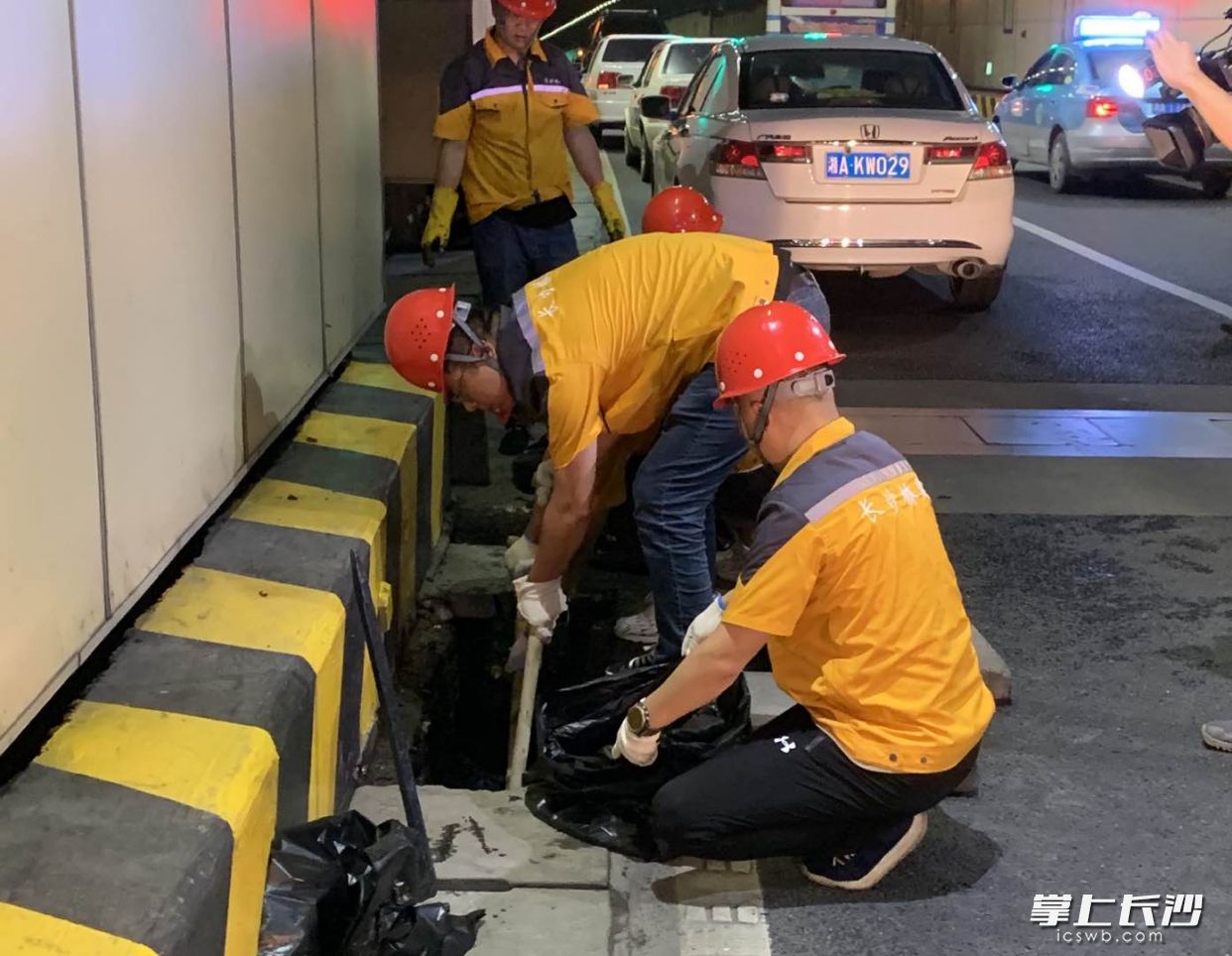 隧道维护人员在营盘路隧道内清理淤泥。