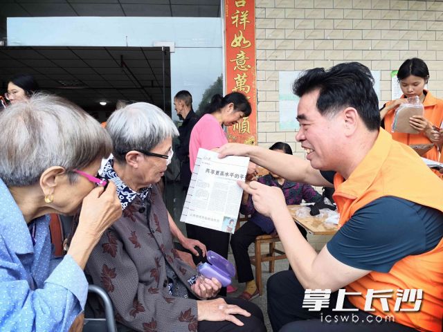 互助会会长邓建明（右一）在为老人免费配置老花镜。长沙晚报全媒体记者 贺文兵 摄