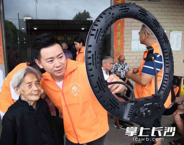 今年99岁、眼不花耳不聋的李爱莲娭毑（左一）被欧尧顺（左二）扶着走到正在直播的手机前，与网友打着招呼一起互动，引来一众粉丝弹幕点赞。长沙晚报全媒体记者 贺文兵 摄