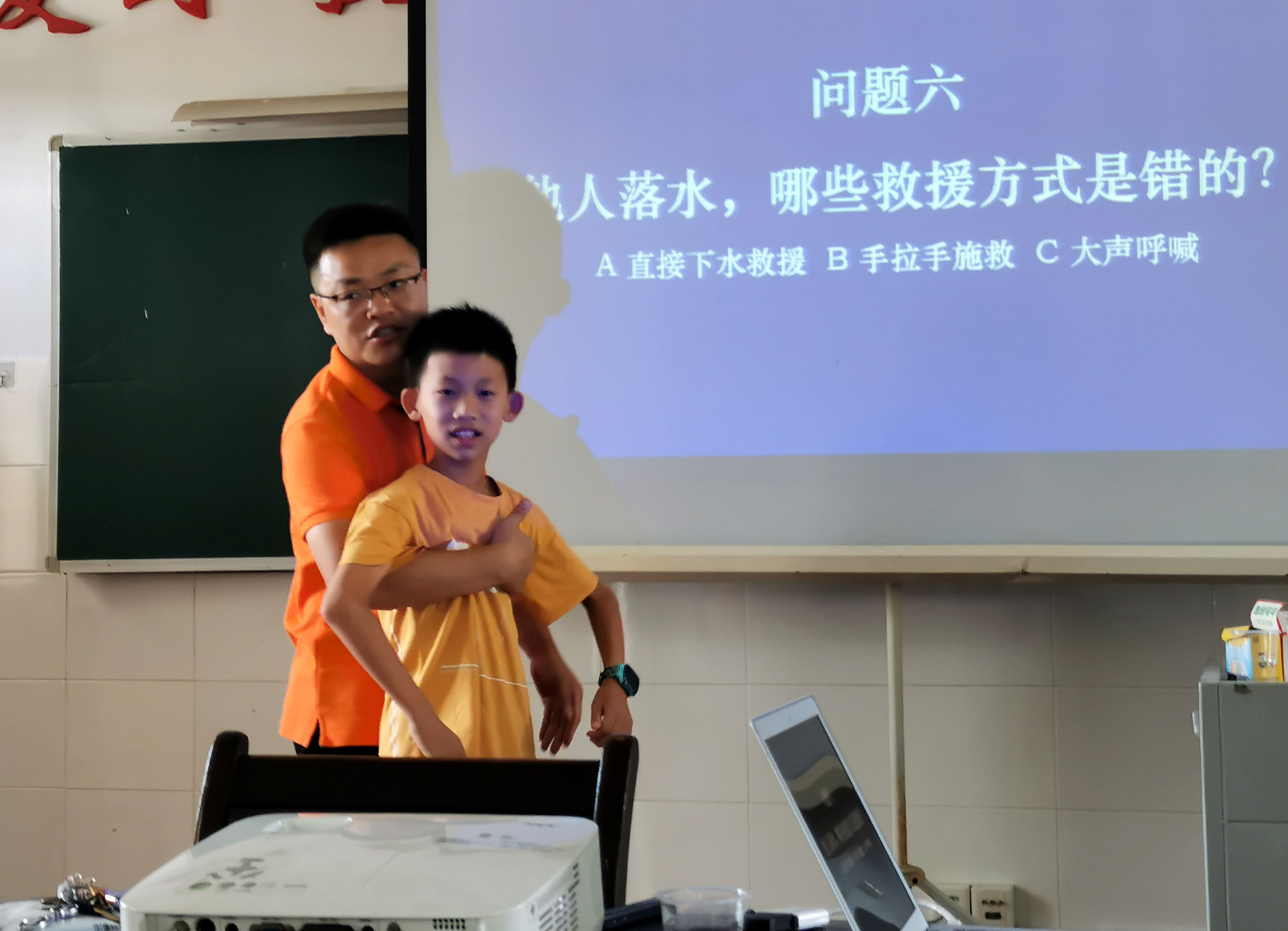 周荣军以《珍爱生命，预防溺水》为题，为家长、孩子讲授防溺水知识 。这是周荣军在向家长演示溺水施救方法。