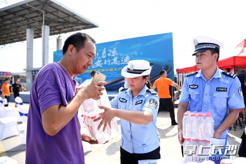 活动现场，高速交警向货车驾驶人发放“交通安全定制水。”