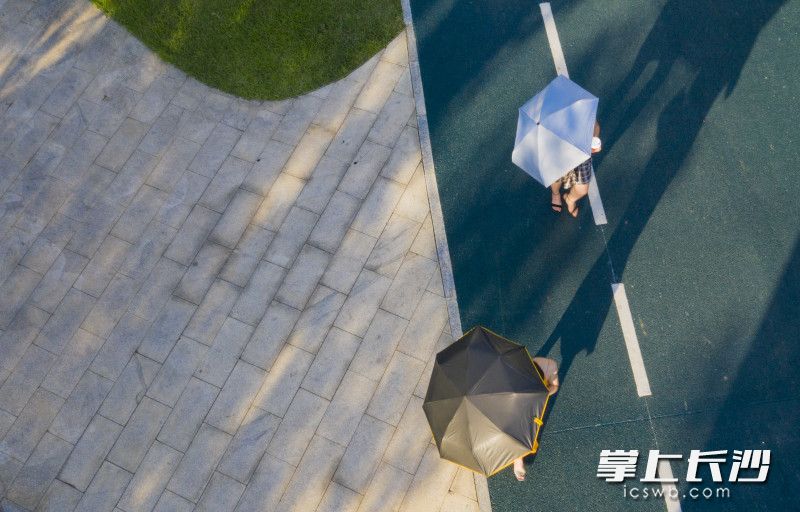 两位游客漫步在小道上，边走边拍照。