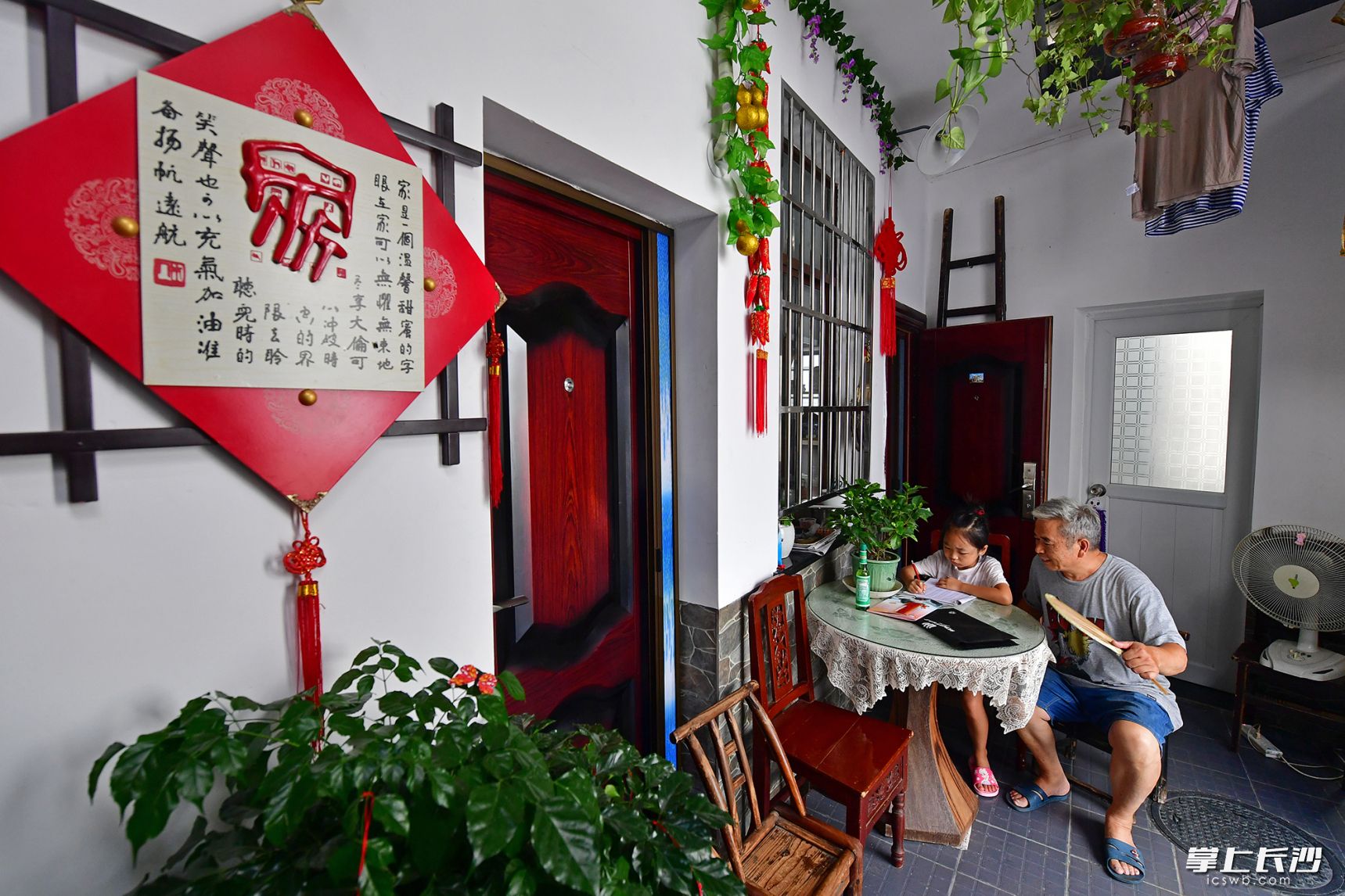 陈杨两家合用的小庭院里，陈裕全在辅导外孙女写作业。长沙晚报全媒体记者 王志伟 摄