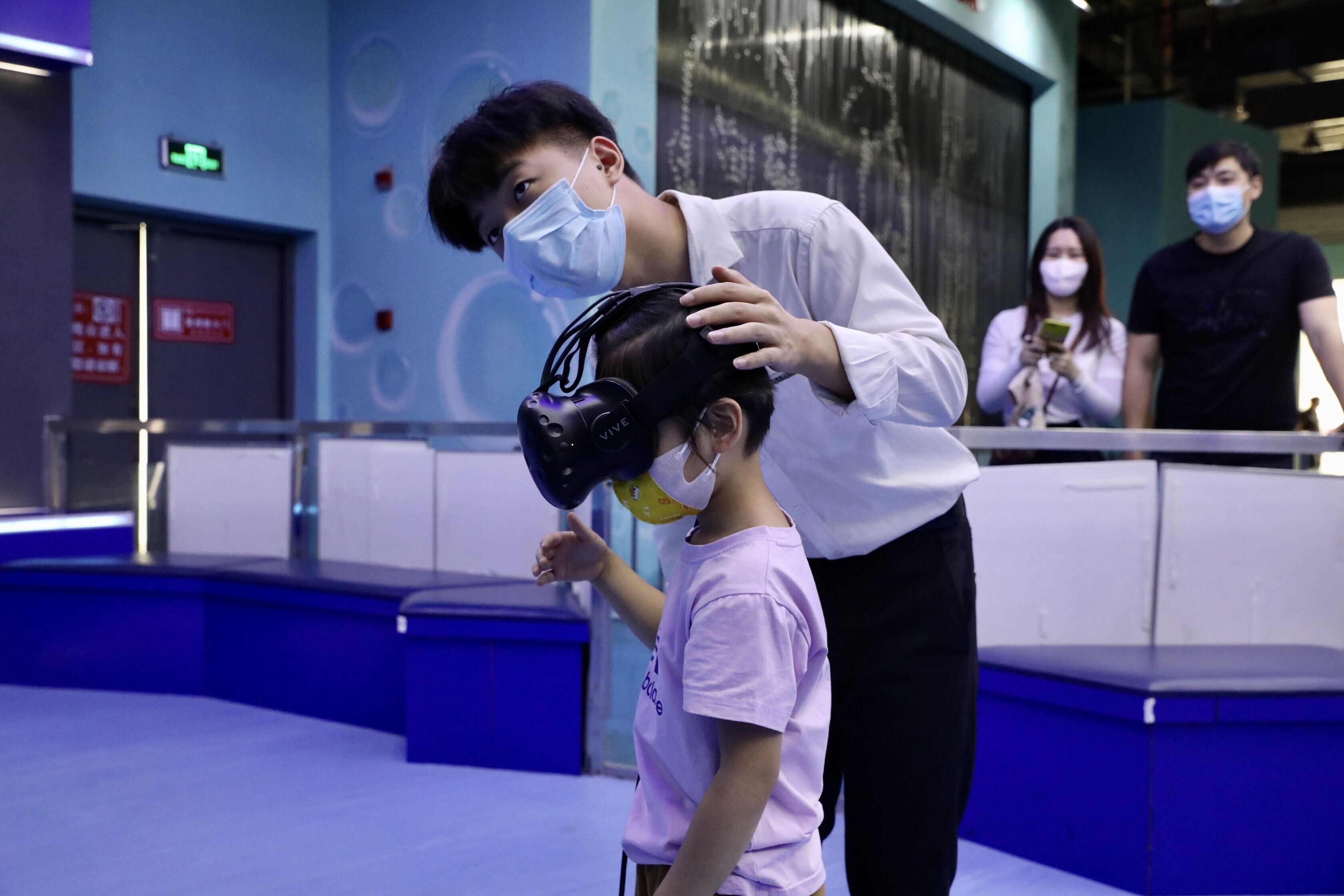 工作人员正在为小朋友调试VR设备