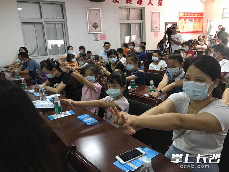 现场的青少年和家长在急救培训导师的指导下，学习海姆立克急救法。