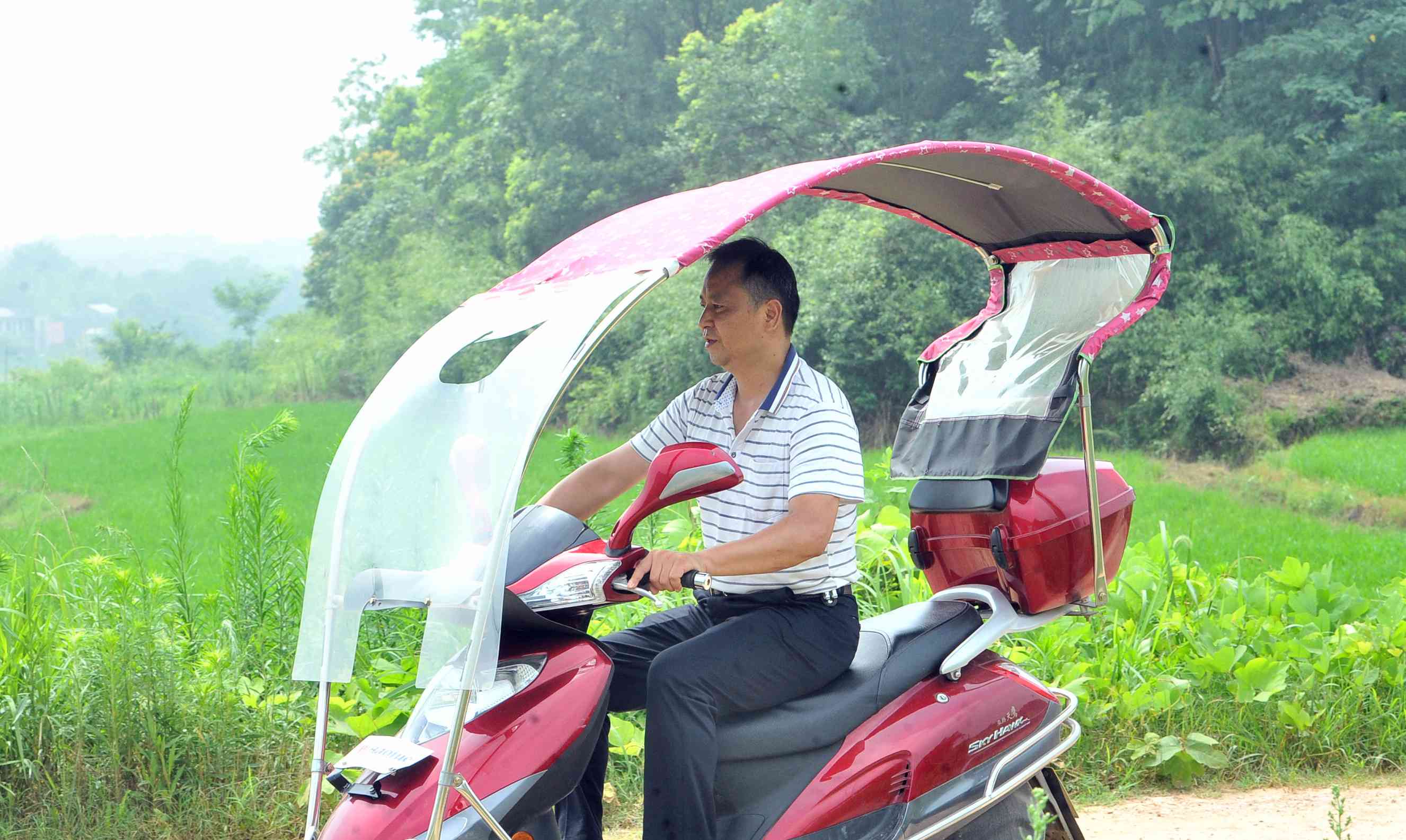龚宇兵骑着摩托车走村串户。
