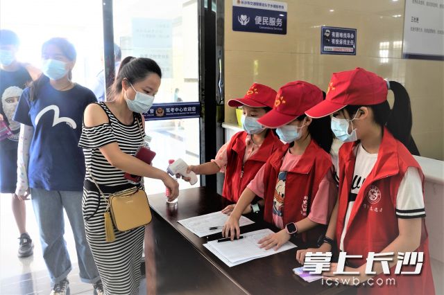 在宁乡市车管所入口处，小学生志愿者正在为进入大厅办理业务的群众测量体温。 长沙晚报全媒体记者 张禹 通讯员 何博文 摄影报道