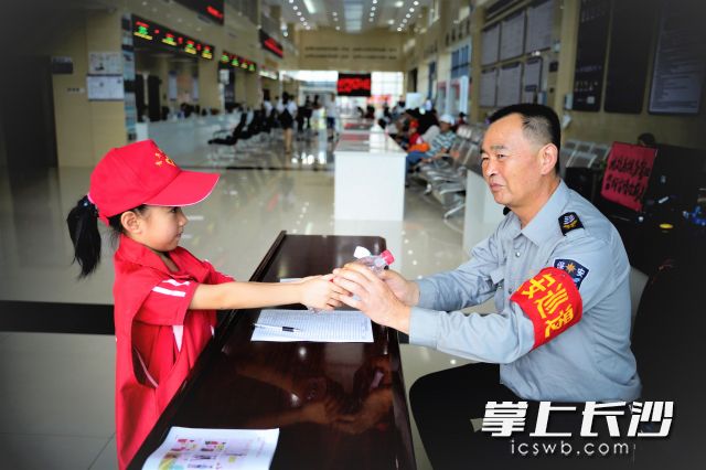“保安伯伯您辛苦啦！请喝口水吧。”来自宁乡市新山小学二年级的小志愿者谭可昕，为车管所的工作人员送上解渴的矿泉水。 长沙晚报全媒体记者 张禹 通讯员 何博文 摄影报道