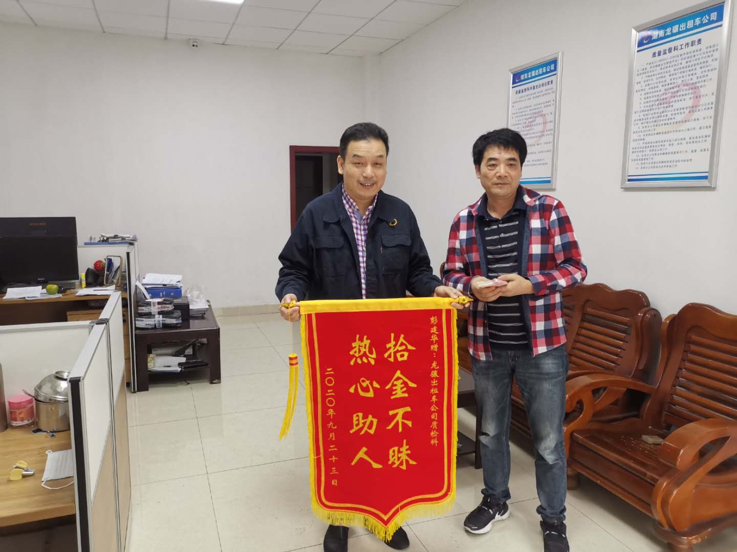 在湖南龙骧出租车公司，乘客彭先生送来锦旗，感谢湘AT9276驾驶员任德贵（左）的拾金不昧。 长沙晚报通讯员 汤娟 摄