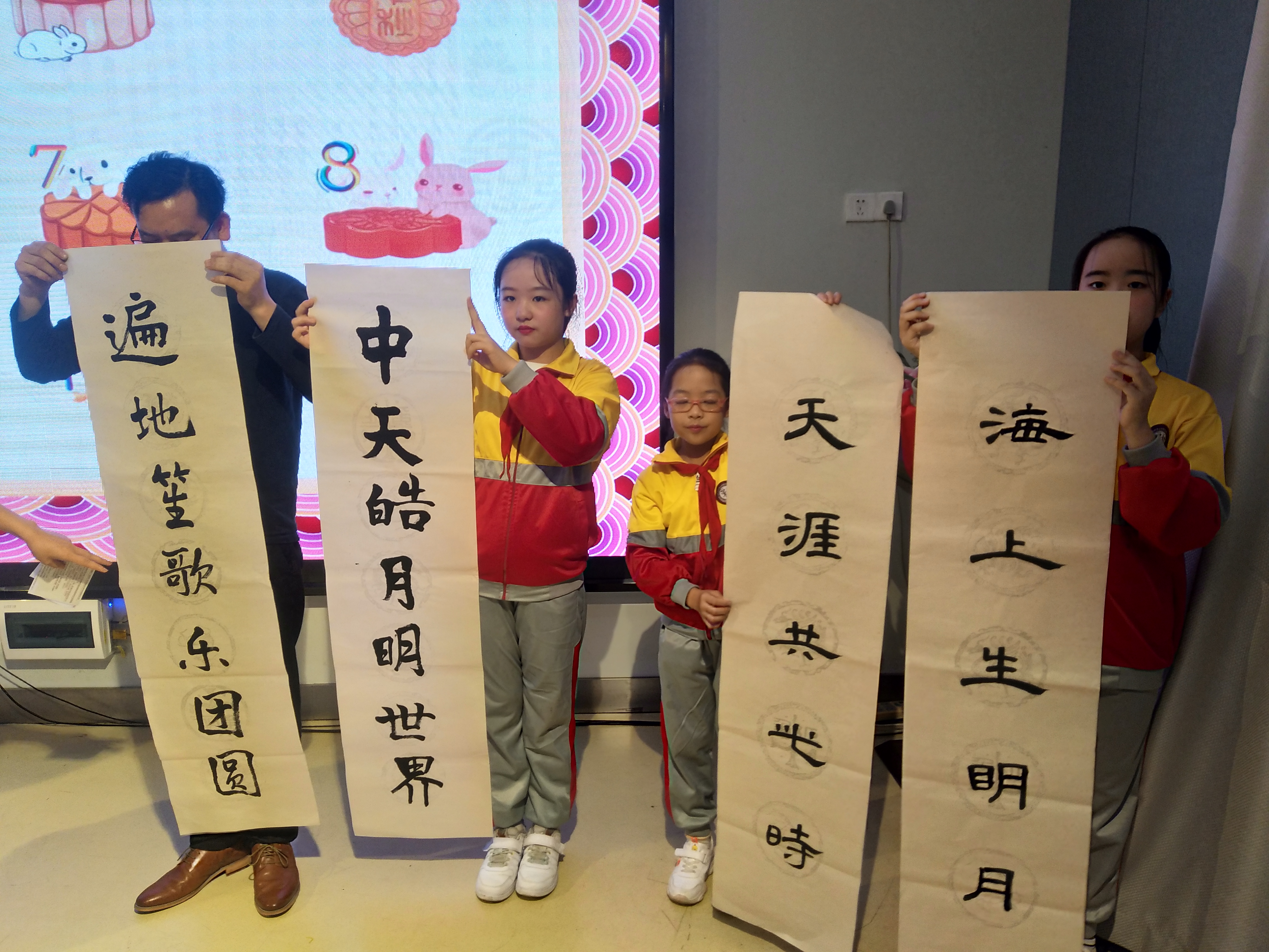 书法班的老师和同学挥笔书写中秋主题对联。